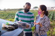 © JackF - Woman and man farm workers wearing face masks for spread viral disease discussing papers standing near car outdoors