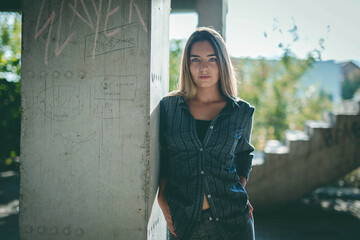 Poster - Young Caucasian female wearing a shirt and jeans posing near a concrete wall