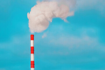 Environmental pollution, environmental problem, smoke from the pipe of an industrial plant or thermal power plant against a blue sky