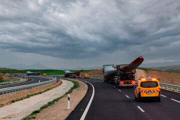 Wall Mural - Special transport trucks with a wind turbine blade each circulating accompanied by signaling vehicles.