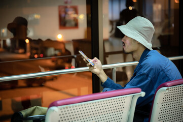 departure person using a phone in aerodrome airport terminal, searching travel trip information on smartphone mobile, waiting a business flight boarding on online cyberspace