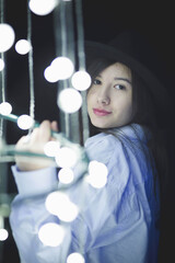 Poster - Young female in casual clothing and a hat posing with city lights at night