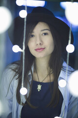 Sticker - Young female in casual clothing and a hat posing with city lights at night