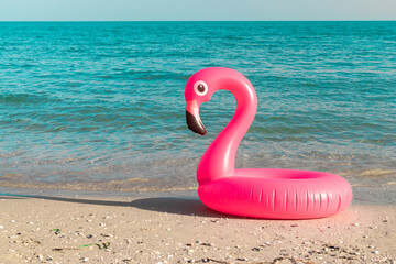 Summer sale. Pink inflatable flamingo in blue ocean water for sea summer beach background. Minimal summer concept.