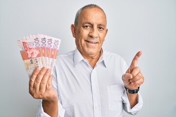 Poster - Handsome senior man holding 100 hong kong dollars banknotes smiling happy pointing with hand and finger to the side