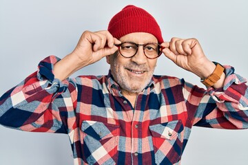 Sticker - Handsome mature man holding glasses, wearing wool hat smiling with a happy and cool smile on face. showing teeth.