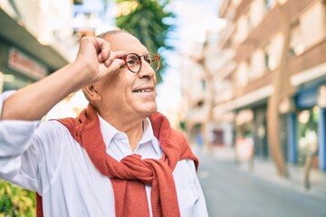 Wall Mural - senior man smiling happy wearing glasses walking at the city.