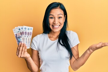 Sticker - Beautiful hispanic woman holding 500 russian ruble banknotes celebrating achievement with happy smile and winner expression with raised hand