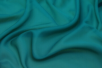 Texture, background, pattern. Texture of green silk fabric. Beautiful emerald green soft silk fabric.