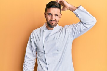 Sticker - Handsome man with beard wearing professional cook uniform confuse and wonder about question. uncertain with doubt, thinking with hand on head. pensive concept.