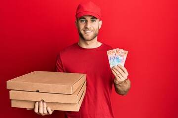 Sticker - Young caucasian man holding delivery box and swiss franc banknotes smiling with a happy and cool smile on face. showing teeth.