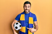 Young Hispanic Man Football Hooligan Soccer Ball Smiling Happy Pointing With Hand And Finger