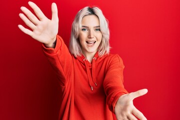 Sticker - Young blonde girl wearing casual clothes pointing thumb up to the side smiling happy with open mouth