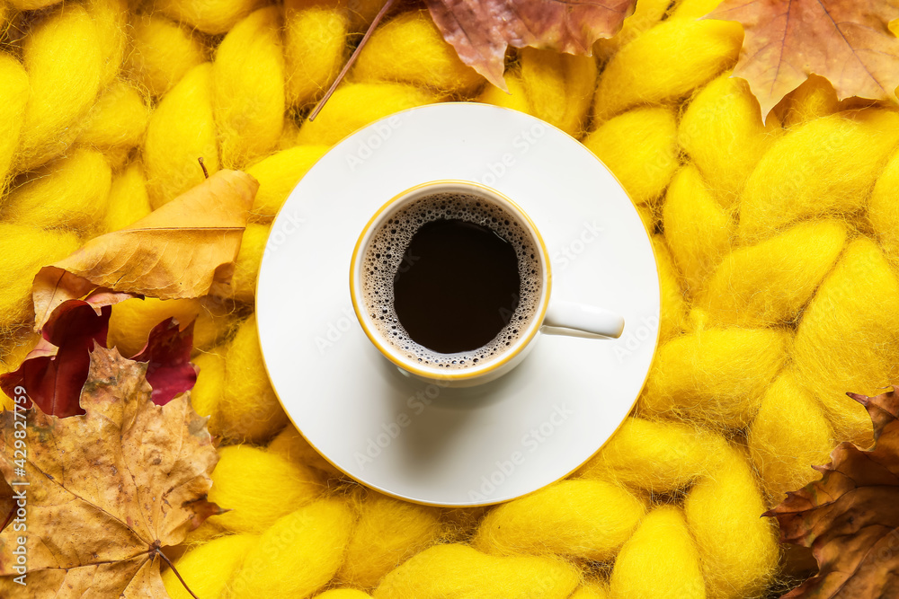 Beautiful autumn composition with cup of coffee on knitted plaid