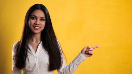 Wall Mural - Young pretty woman points to something - studio photography