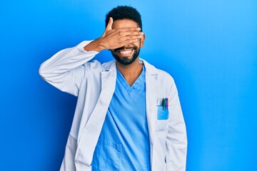 Wall Mural - Handsome hispanic man with beard wearing doctor uniform smiling and laughing with hand on face covering eyes for surprise. blind concept.