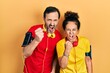 © Krakenimages.com - Middle age couple of hispanic woman and man wearing sportswear and arm band angry and mad raising fist frustrated and furious while shouting with anger. rage and aggressive concept.