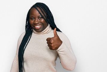 Sticker - Young black woman with braids wearing casual winter sweater smiling happy and positive, thumb up doing excellent and approval sign