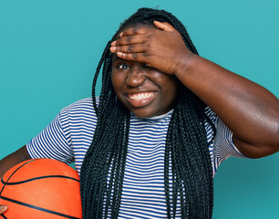 Sticker - Young black woman with braids holding basketball ball stressed and frustrated with hand on head, surprised and angry face