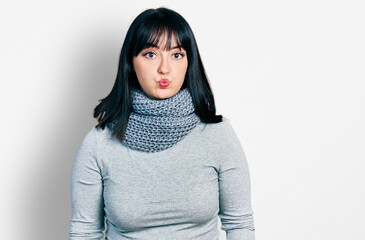 Poster - Young hispanic plus size woman wearing winter scarf puffing cheeks with funny face. mouth inflated with air, crazy expression.