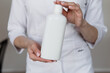 © sadreevaa - young girl doctor holding a white bottle of shampoo in his hands with a manicure