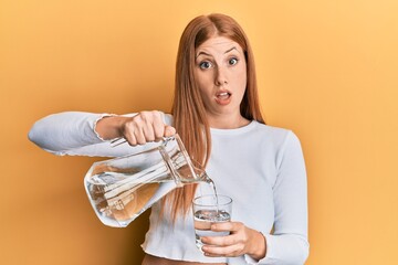 Wall Mural - Young irish woman pouring water clueless and confused expression. doubt concept.