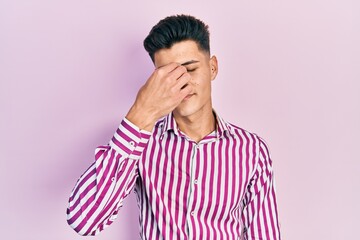 Wall Mural - Young hispanic man wearing casual clothes tired rubbing nose and eyes feeling fatigue and headache. stress and frustration concept.