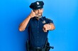 © Krakenimages.com - Middle age handsome man wearing police uniform smiling doing talking on the telephone gesture and pointing to you. call me.