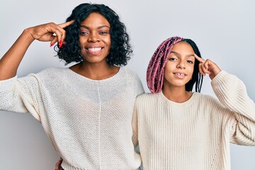 Poster - Beautiful african american mother and daughter wearing casual clothes and hugging smiling pointing to head with one finger, great idea or thought, good memory