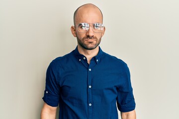 Poster - Young hispanic man wearing casual clothes and glasses with serious expression on face. simple and natural looking at the camera.