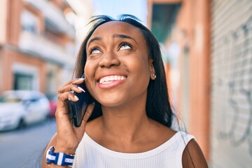 Young african american woman smiling happy talking on the smartphone at the city.