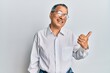 © Krakenimages.com - Middle age indian man wearing casual clothes and glasses smiling with happy face looking and pointing to the side with thumb up.