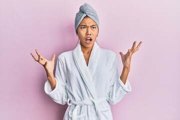 Poster - Young chinese woman wearing shower towel cap and bathrobe crazy and mad shouting and yelling with aggressive expression and arms raised. frustration concept.