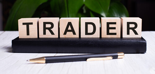 Fototapete - The word TRADER is written on the wooden cubes of the diary near the handle.