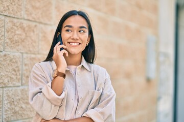 Poster - Young latin girl smiling happy talking on the smartphone at the city.