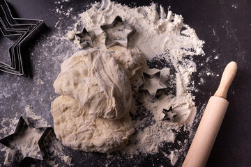 Flour, rolling pin, cookie cutters on a dark background. Preparation for baking.