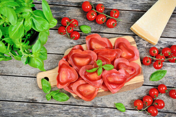 Canvas Print - Red heart ravioli with tomato, mozzarella and basil on table