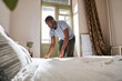 © Yakobchuk Olena - Man making his bed early in the morning while looking calm
