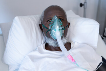 African american male patient lying on hospital bed wearing oxygen mask ventilator