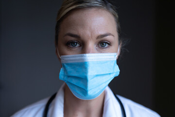 Wall Mural - Portrait of caucasian female doctor wearing mask looking to camera