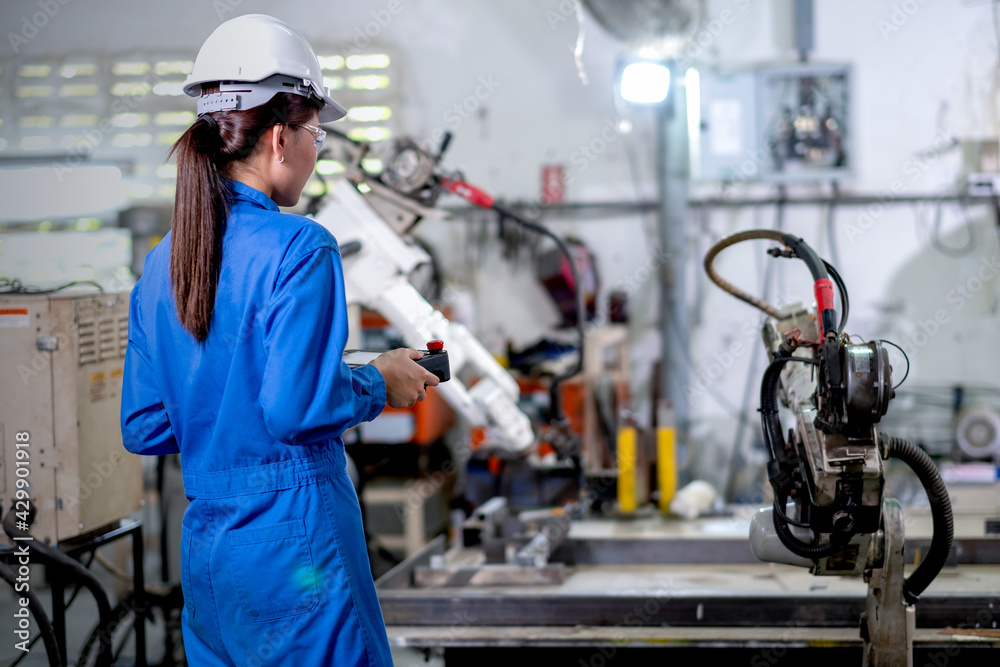 Back of factory worker woman hold controller to control metal welding ...