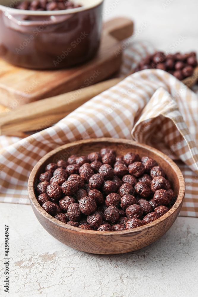 Bowl with chocolate corn balls on light background