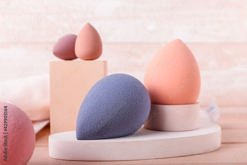 Composition with makeup sponges on light wooden background, closeup