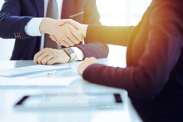 Businesspeople or lawyers shaking hands finishing up meeting or negotiation in sunny office. Business handshake and partnership