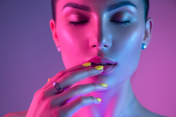 Wall Mural - High Fashion model girl in colorful bright UV lights posing in studio, portrait of beautiful woman with trendy make-up and manicure. Art design, colorful make up. Over colourful purple background. 