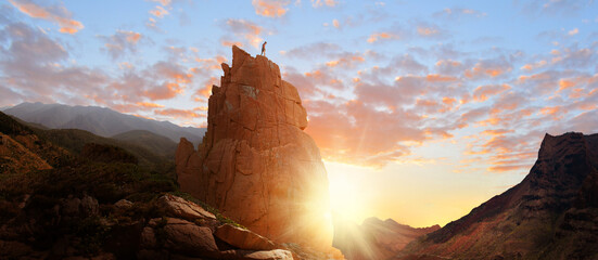 Woman free climbing freely hiking adventure on rocks canyon in the mountains at sunrise - landscape great hiking success business.