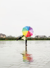 Woman Holding Colorful Umbrella Dancing In The Rain
