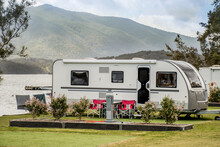 RV Caravan Camping At The Caravan Park On The Lake With Mountains On The Horizon. Camping Vacation Travel Concept