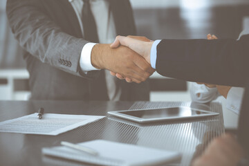 Handshake as successful negotiation ending, close-up. Unknown business people shaking hands after contract signing in modern office