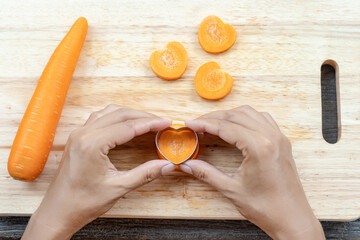 Wall Mural - Heart crafting on the carrot with hands pressing. heart shaped aluminium vegetables stamp